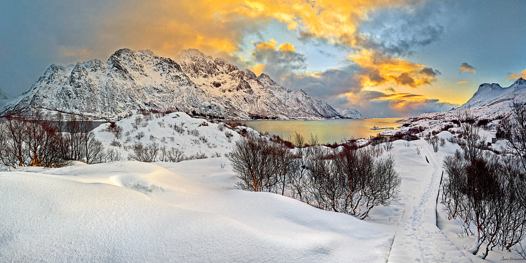 Snow-covered landscape with golden sky over Norwegian fjords and mountains
