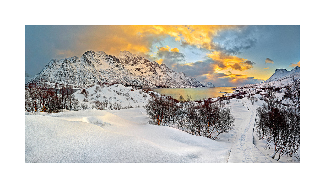 Fine art photograph of a snowy trail under fiery sky and rugged peaks