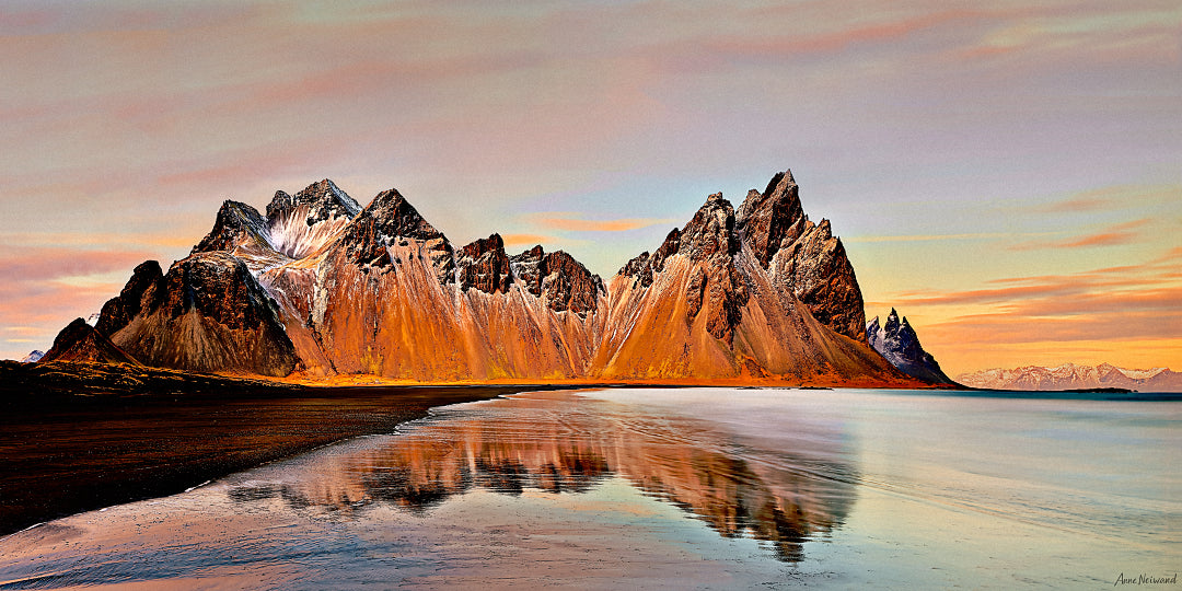 Golden light on Vestrahorn mountain reflecting in still water, Iceland landscape