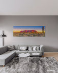 Panoramic photograph of Uluru glowing at sunrise in Australian Outback