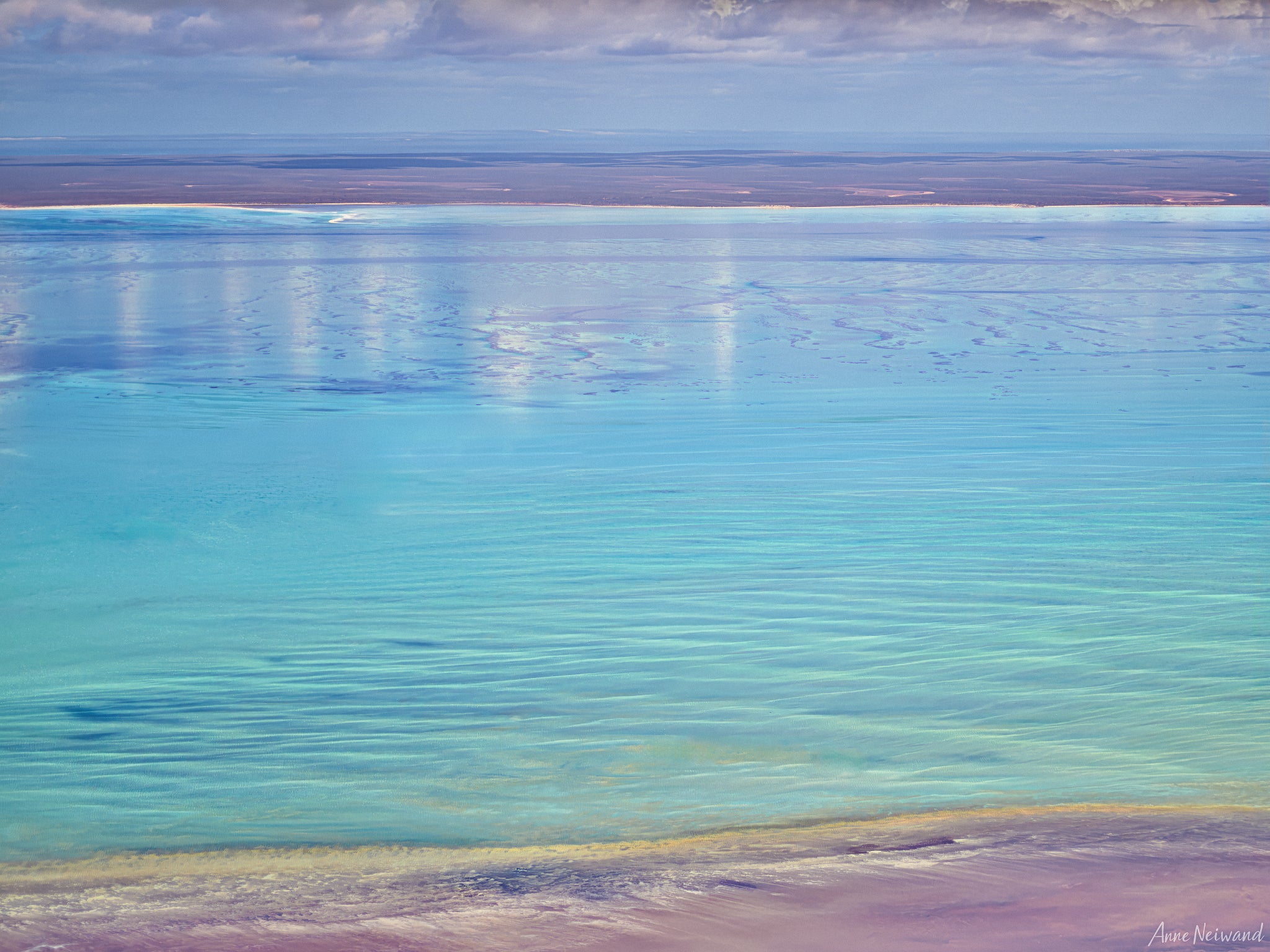 Aerial view of shimmering turquoise water with soft cloud reflections